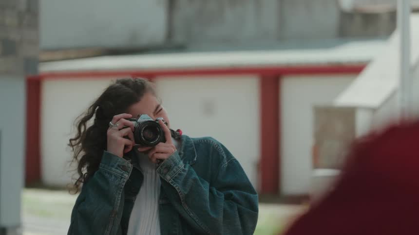 Woman taking a photo with a film camera in an urban area