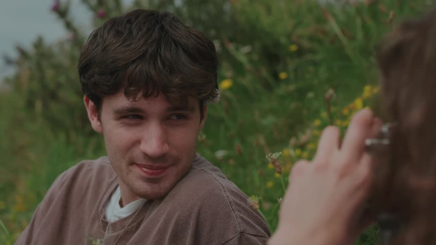 Man sitting on the grass looking at someone taking his picture