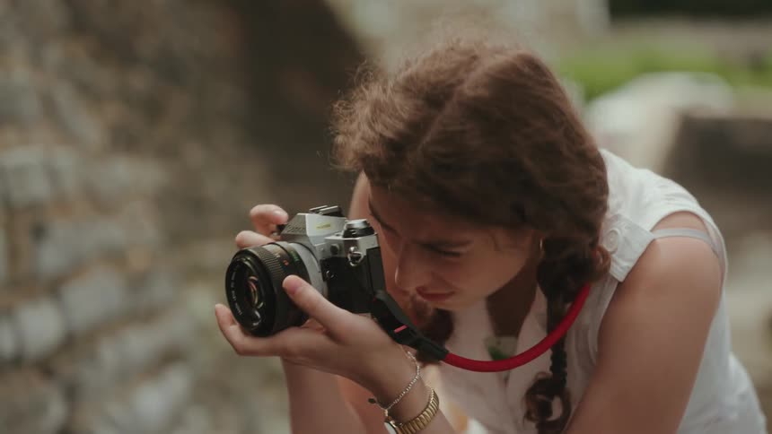 A woman tries to use a professional camera to take a photo but something isnt working