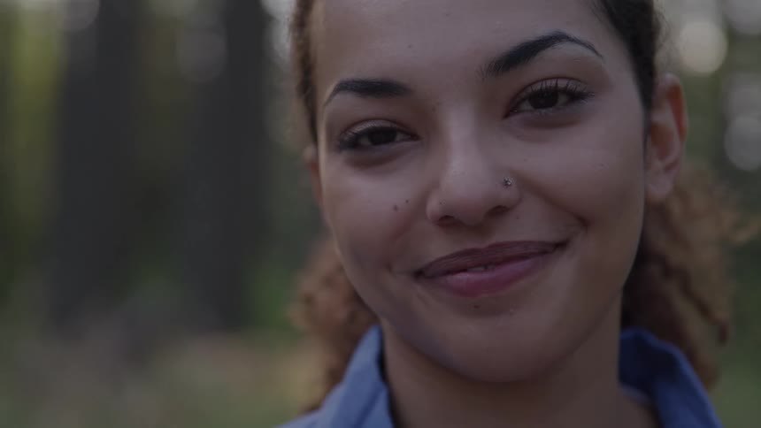 Woman smiling softly in a closeup wearing a blue shirt
