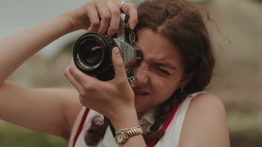 A girl focuses her vintage 35mm film camera