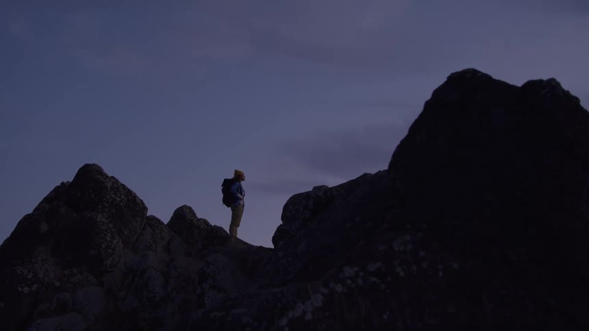 Hiker wearing a backpack stands on a mountain