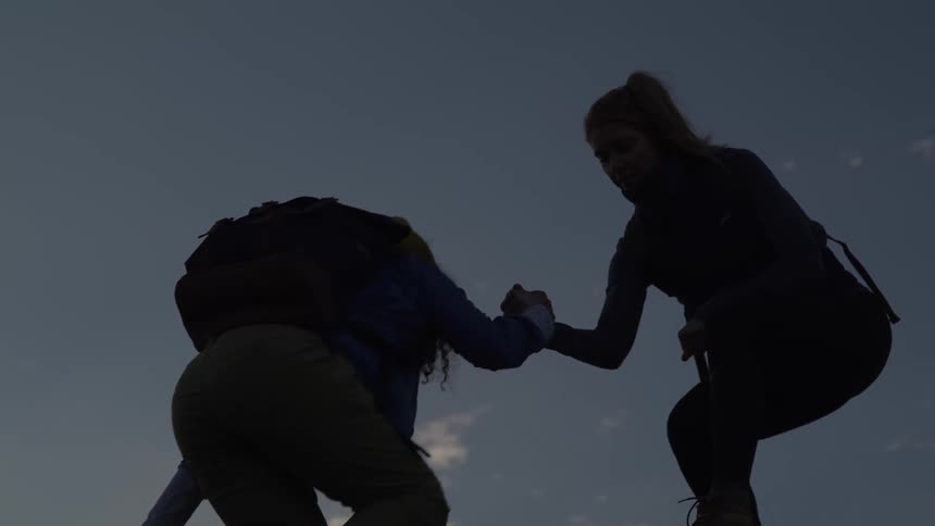 Person helping another climb while hiking