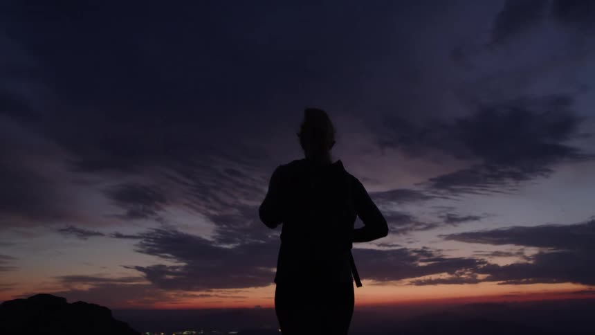Person seen from behind watching the sunset on the horizon