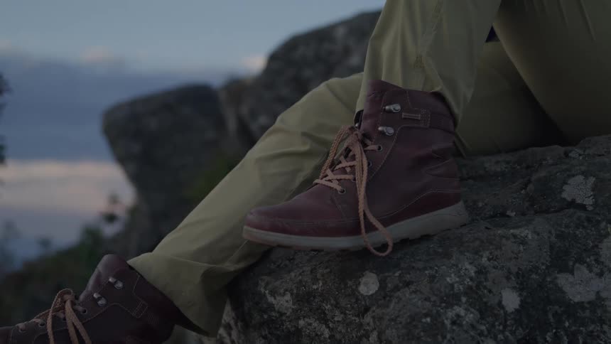 Person wearing brown boots and khaki pants sitting on a rock