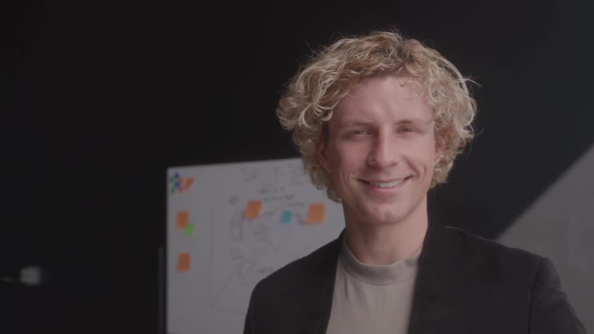 A blonde man smiles at the camera