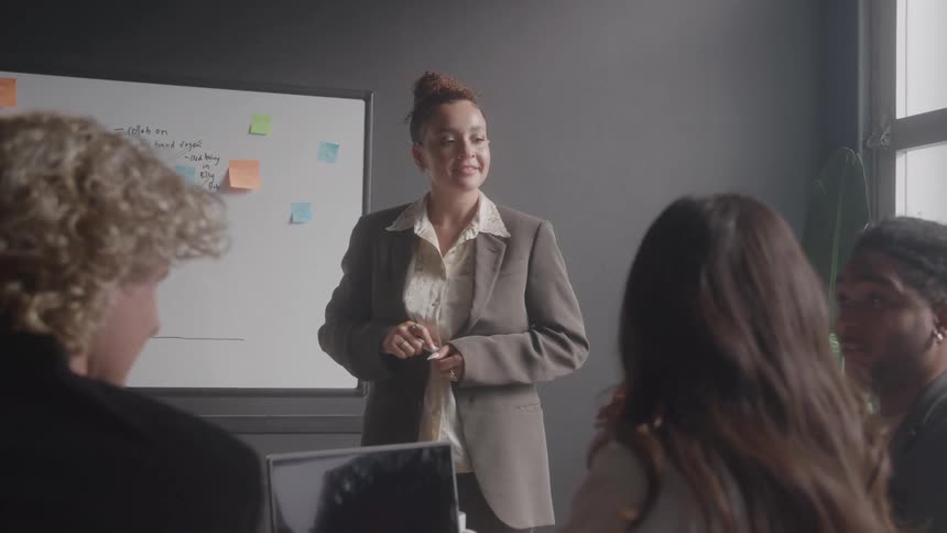 Woman stands presenting information to colleagues in a work meeting