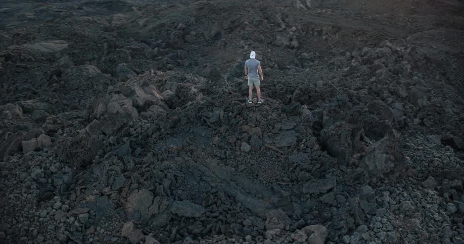 Man stands on rocks on top of a mountain looking all around