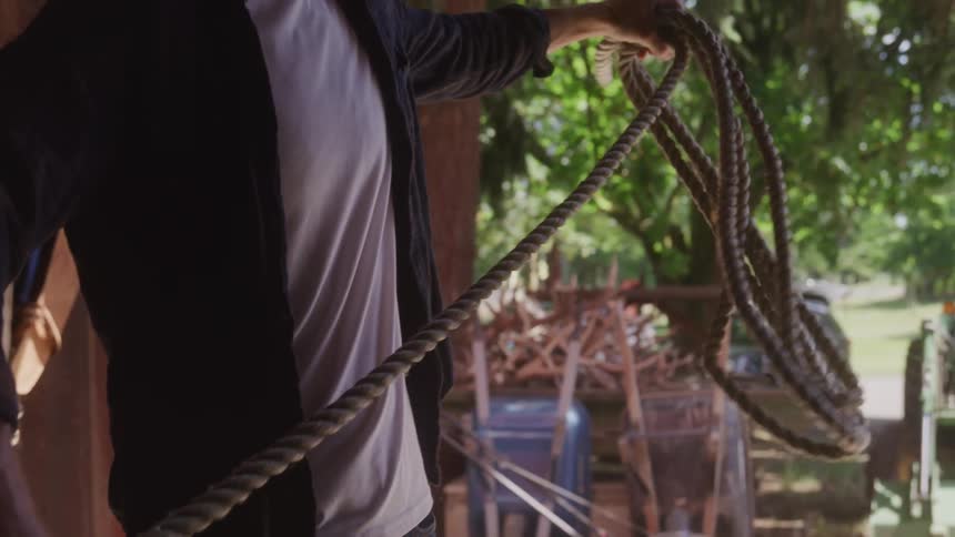 A man holds a rope in an outdoor barn setting