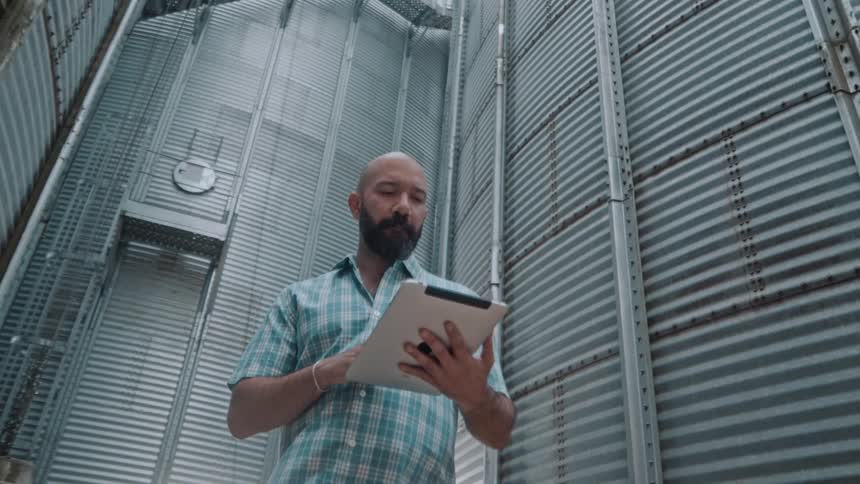 Man inspecting a metal silo interior using a tablet