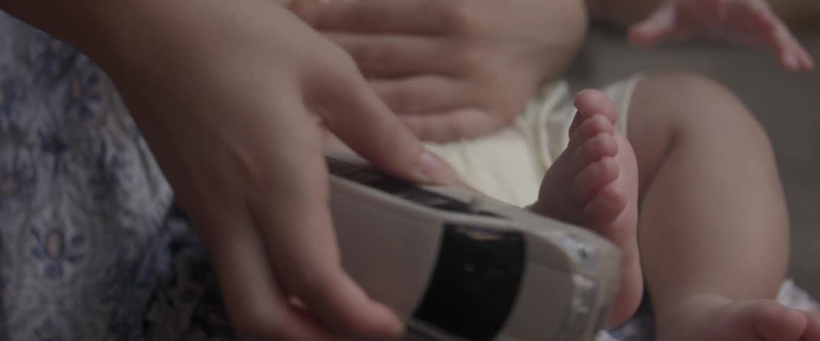 A close up view of someone running a toy car down a baby's leg