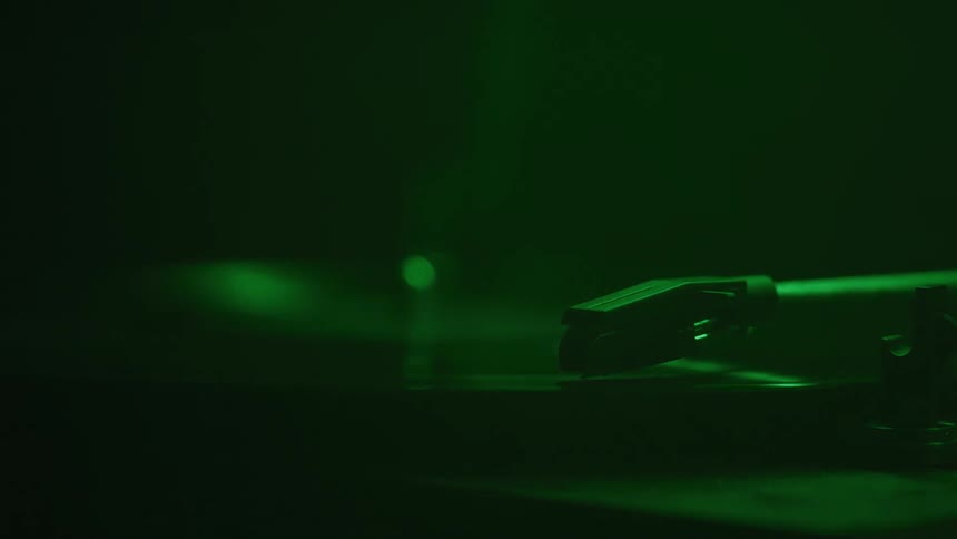 A record player playing a record under green light