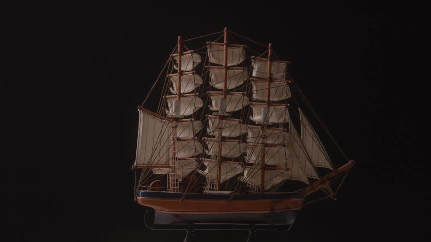 Model of a tall ship stands against a dark background