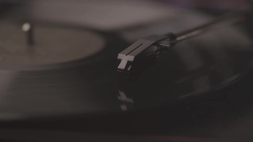 A record players tonearm rests on a spinning vinyl record