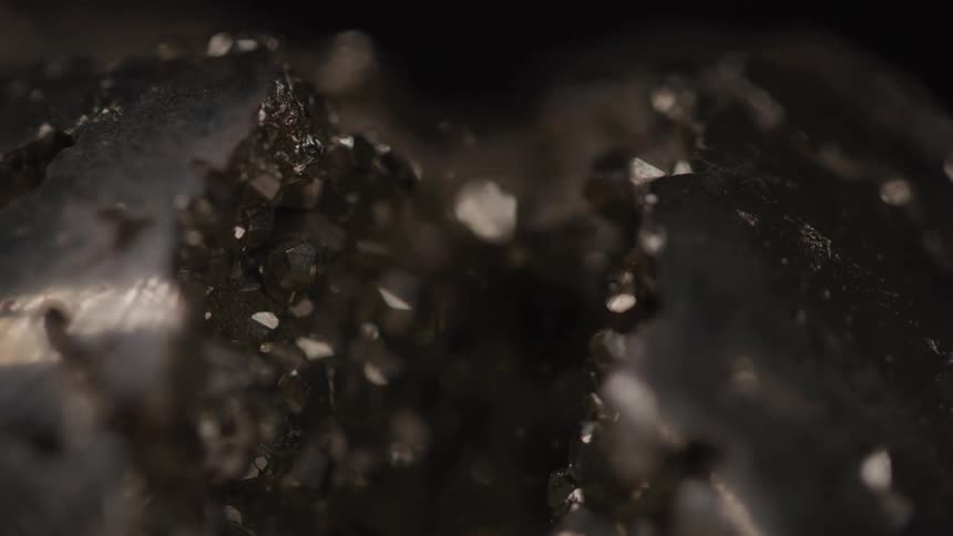 A closeup of a dark geode reveals sparkling crystal formations inside
