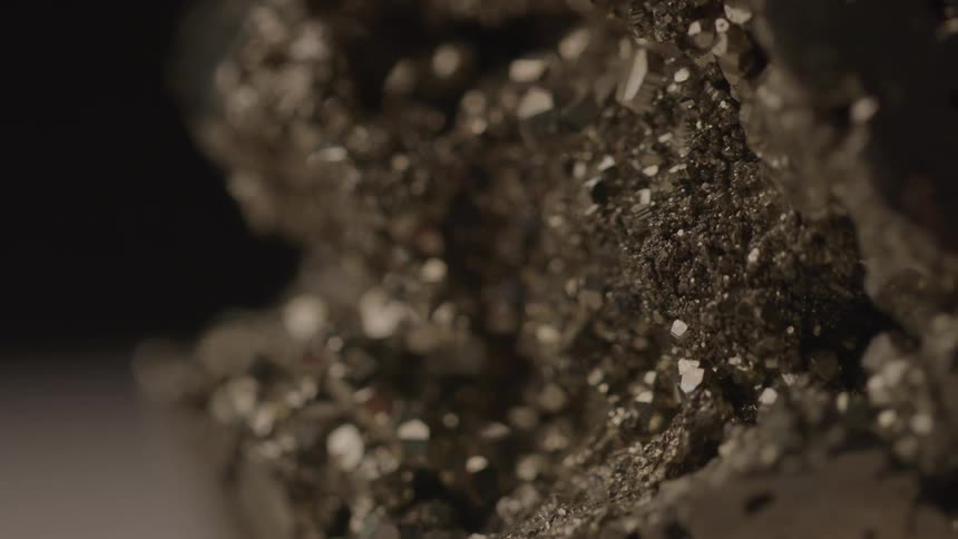 The video shows a closeup of a dark crystalline mineral likely pyrite with many small glittering facets the camera slowly moves over the surface highlighting the shimmering details