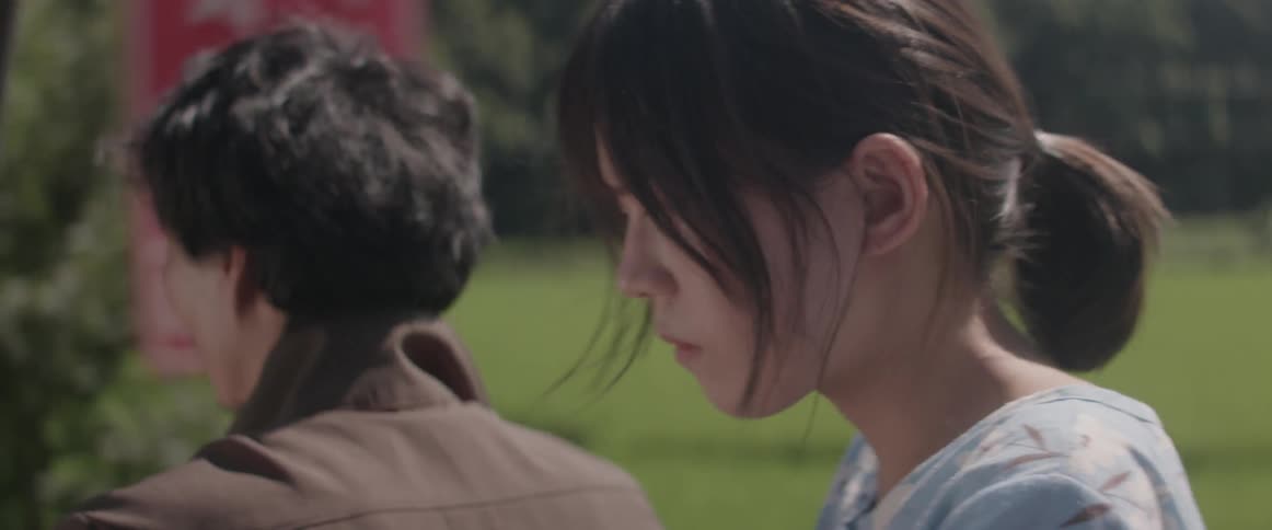 An asian woman rides on a motorcycle behind a man