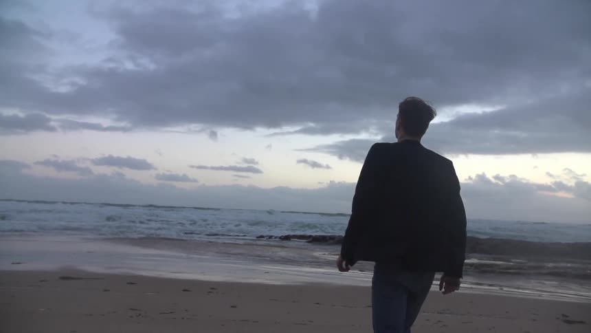 Man walking on a beach at dusk