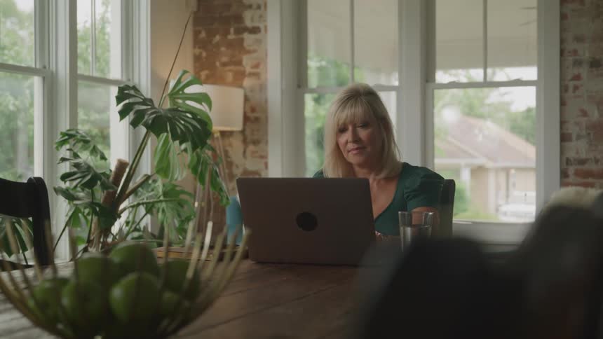 Woman sitting at a table typing on a laptop