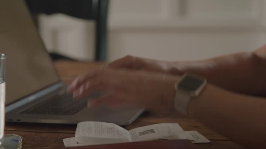 Person holding a receipt next to a laptop