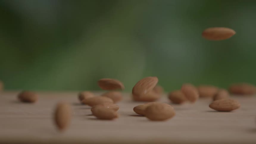 Almonds falling onto a wooden surface