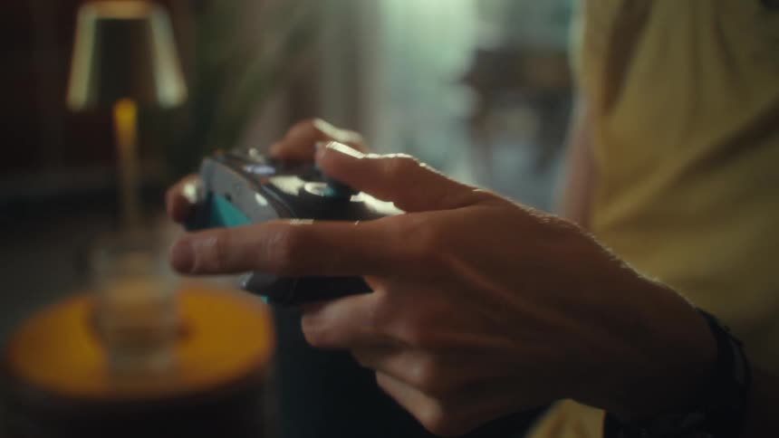 A female hand holding and using a gaming controller while seated in the living room