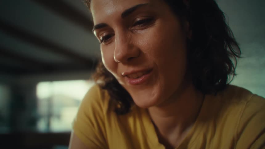 Close up portrait of a young woman smiling while texting with her phone in a room during daytime