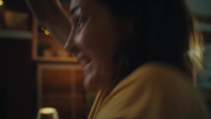 Close up portrait of a young woman celebrating while watching tv in a living room during daytime