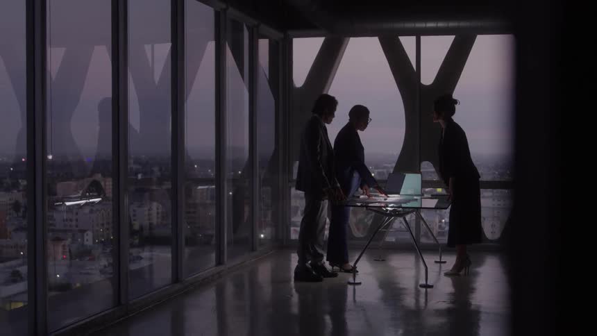Three people around a table talking in an office setting