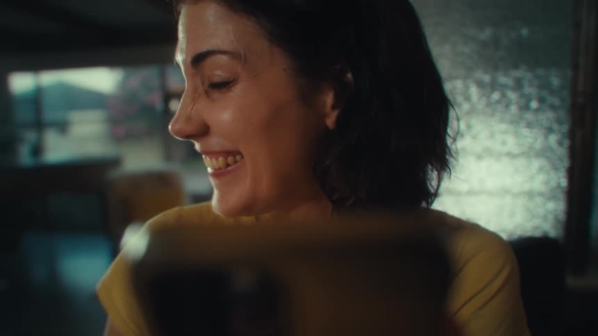 Woman smiling broadly while looking at a cellphone in front of her