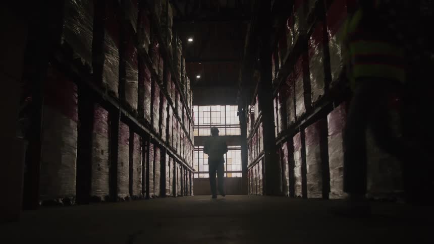 The worker walks in warehouse looking at inventory
