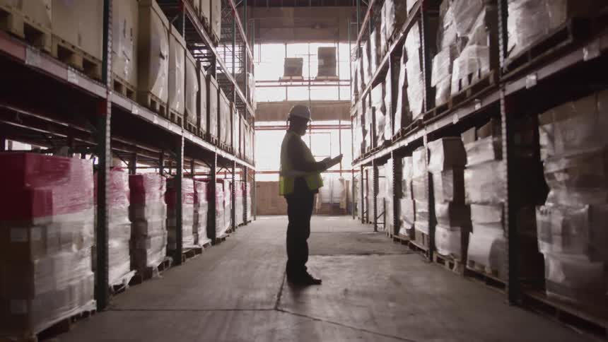 A man is checking inventory in the aisle of the warehouse