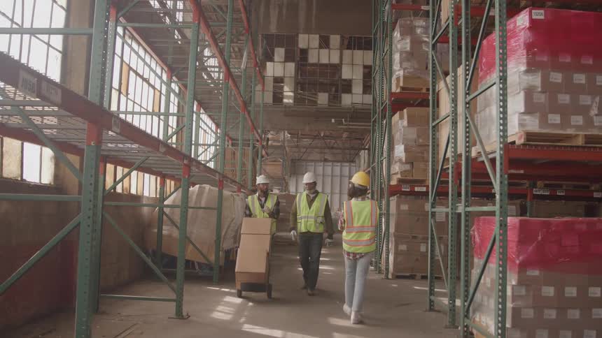 Warehouse workers walking around while moving package boxes in a warehouse during daytime