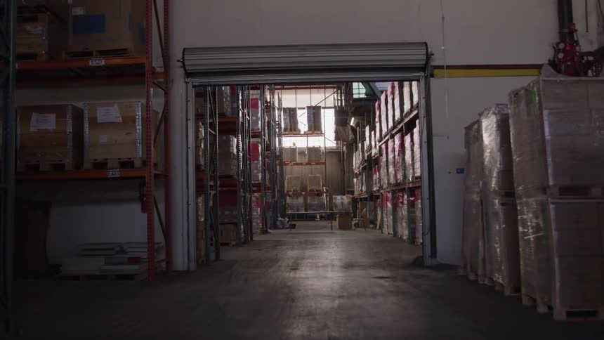 A shipping warehouse filled with shipping boxes stacked on shelves at midday