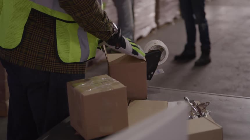 Three workers in a warehouse with boxes talking