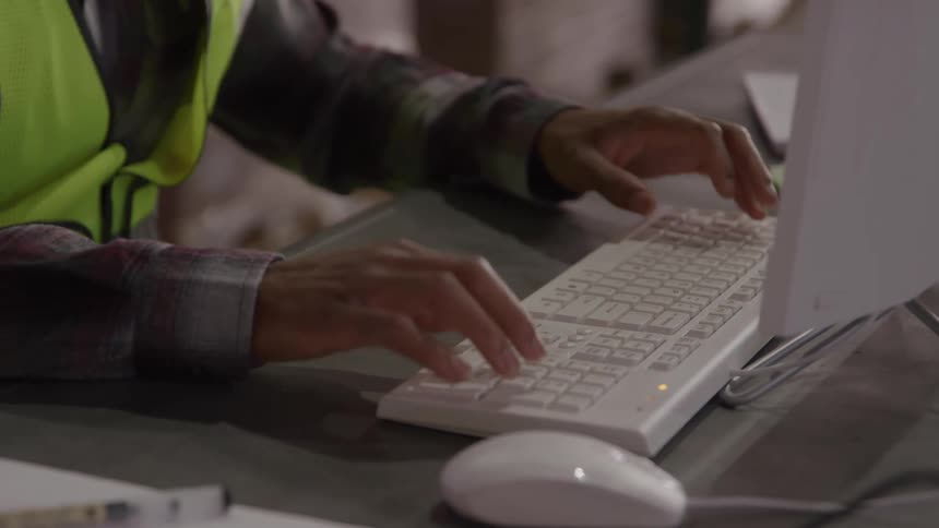 Hands of a person typing on a white keyboard connected to a computer