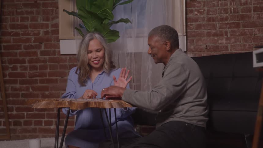 A man and a woman sitting and playing a board game on a table