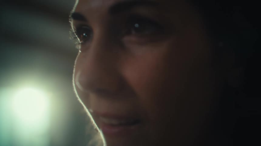 A close view of a woman with dark hair shows her looking off to her right as her smile widens as she plays videog ames
