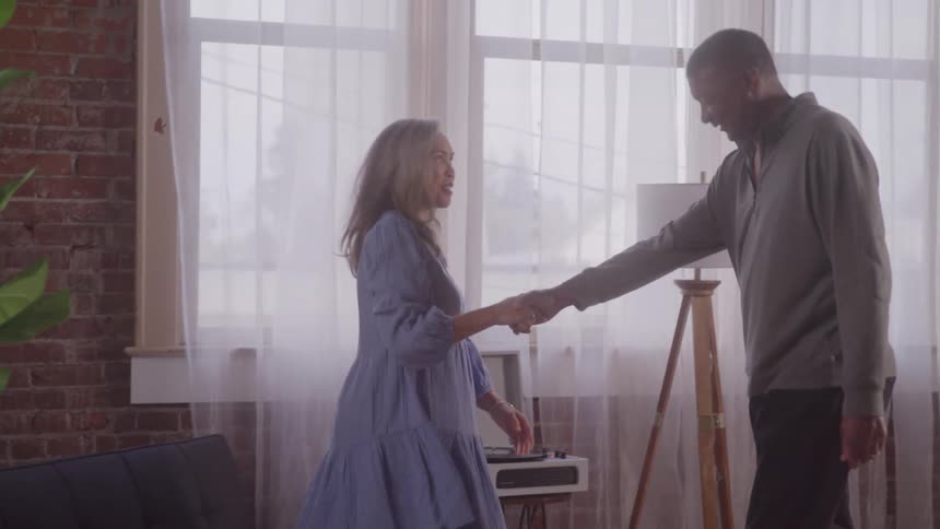 Man taking his wifes hand and asking her to dance
