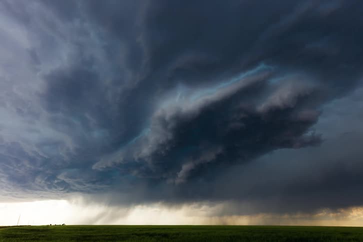 Dark clouds cover the sky over a grassland at midday signaling an approaching storm