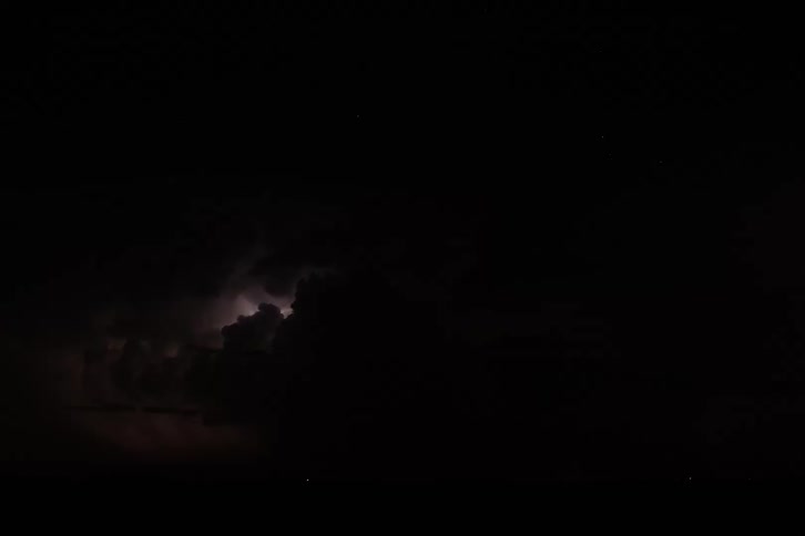 Lightning illuminates dark storm clouds at night