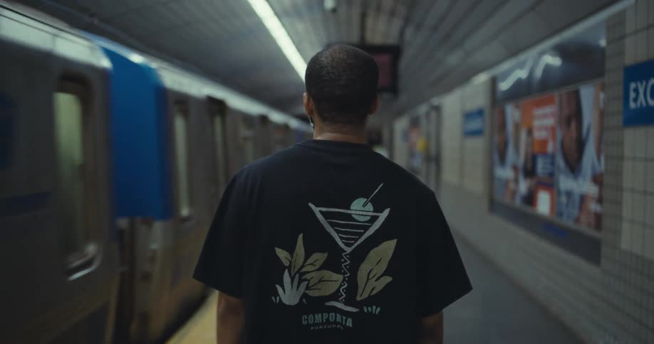 Man walks through a transit station slowly while the train passes in the opposite direction