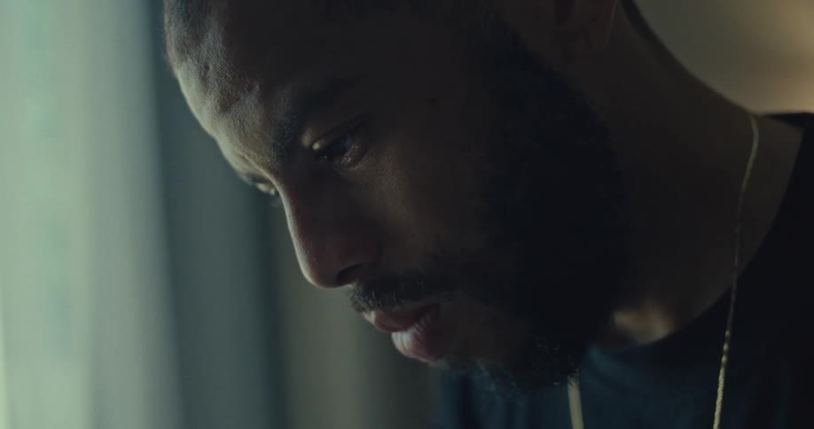A man gazes downward in deep thought indoors
