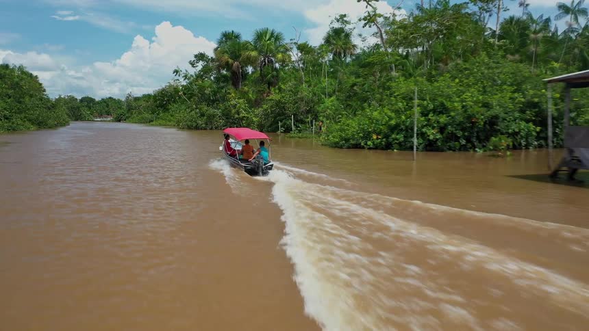 Boat sailing on a river surrounded by vegetation and riverside houses