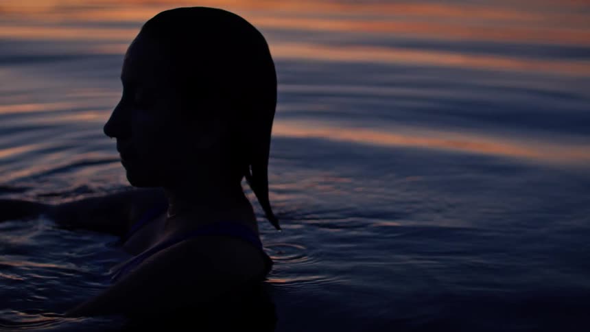 A woman in the sea water at sunset