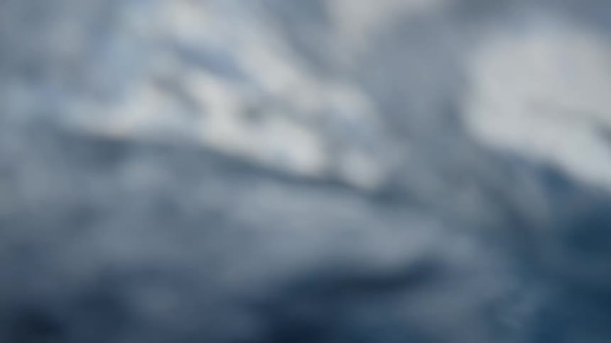 A sea with blue water and a sky filled with large white clouds