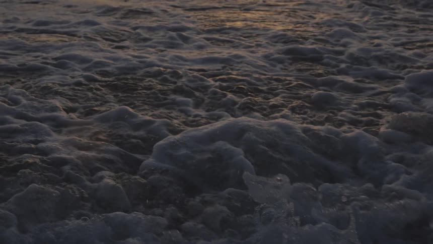 Surf foams while flowing onto the beach