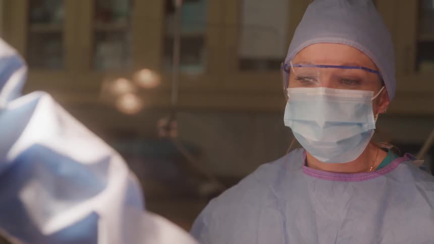 Healthcare professional wearing surgical attire mask and protective glasses in a hospital setting
