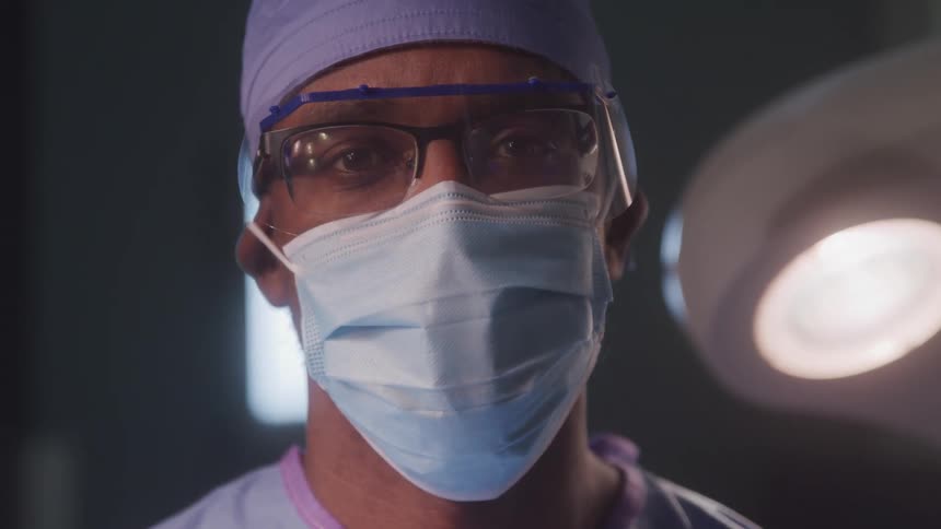 Surgeon wearing a mask protective glasses and cap in the operating room