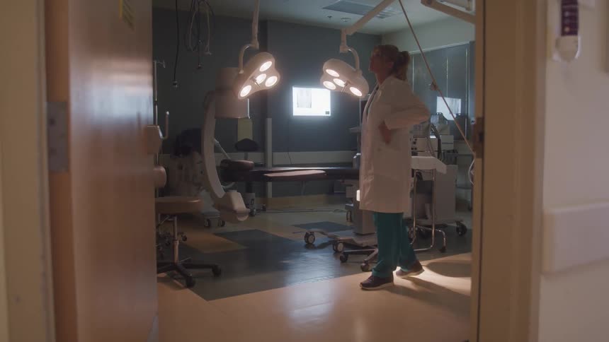 Healthcare professional walks thoughtfully inside an operating room
